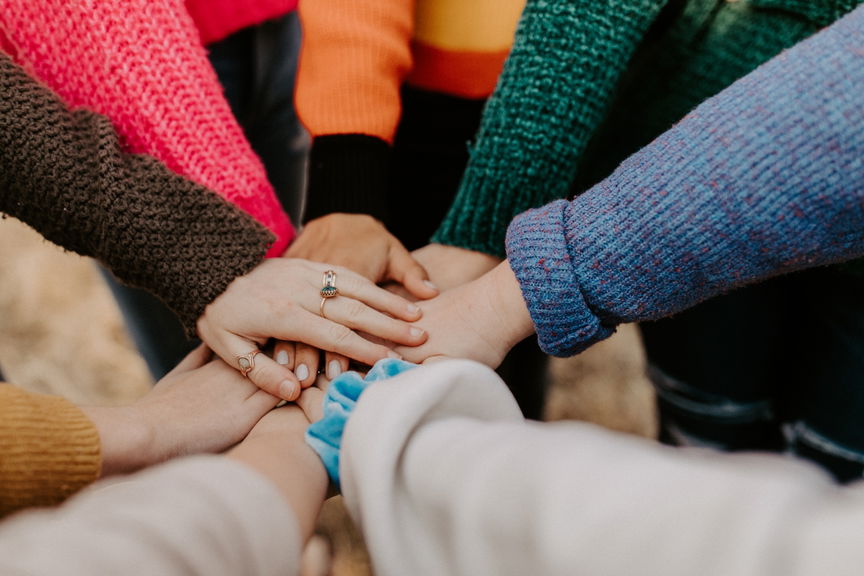 Group of people placing their hands together in the centre, representing teamwork