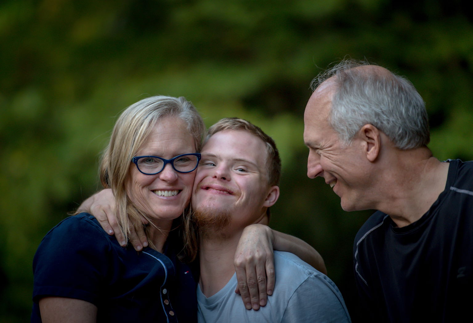 Boy with Down syndrome smiling with his mother and father.
