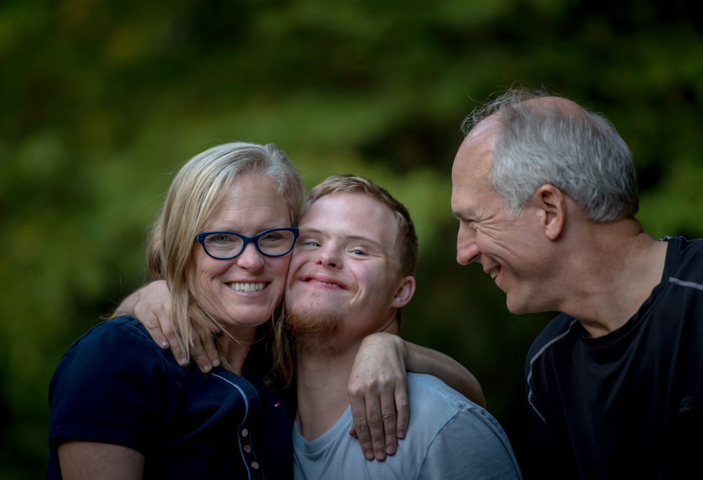 Boy with Down syndrome smiling with his mother and father.