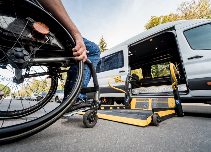 Person using a wheelchair boarding an accessible vehicle via a lift