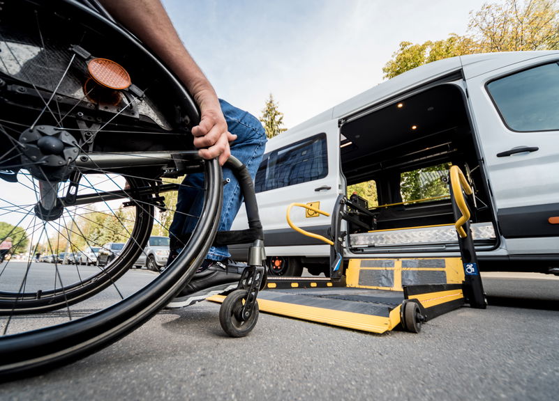 Person using a wheelchair boarding an accessible vehicle via a lift