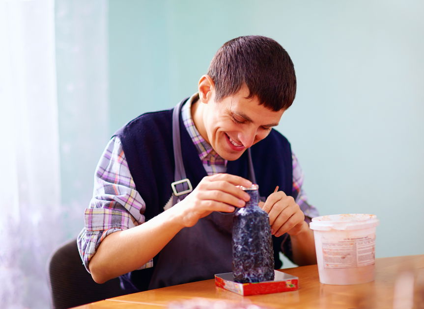 Smiling young man with a disability engaged in a hands-on craft activity