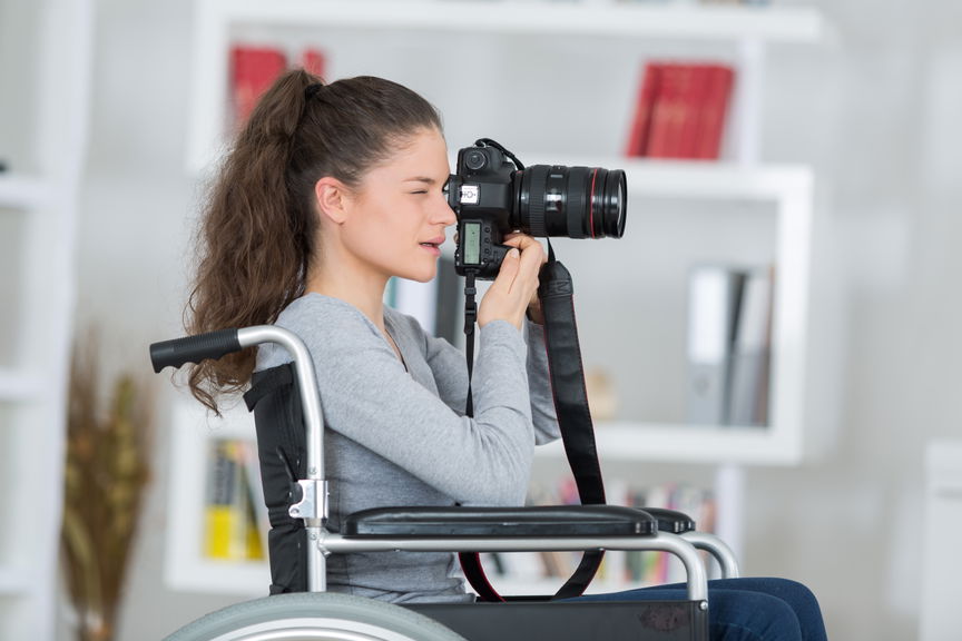 Woman using a wheelchair holding a camera as a photographer