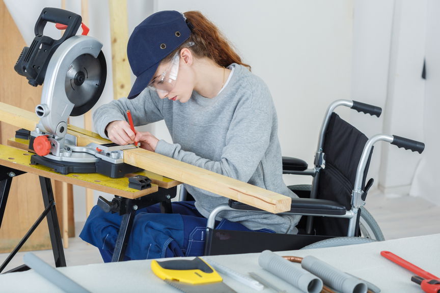 Woman using a wheelchair working with timber in a carpentry workshop
