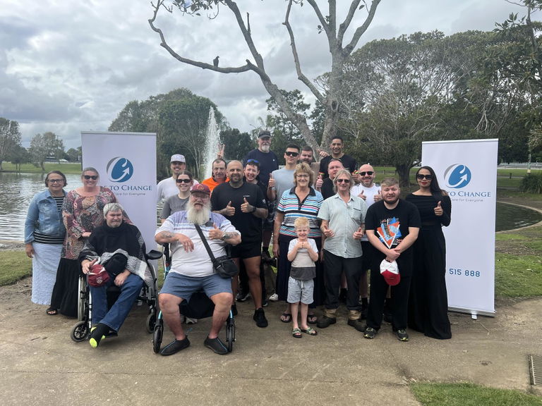 Group of Care to Change participants and volunteers posing together at a Walk for Awareness event by the water