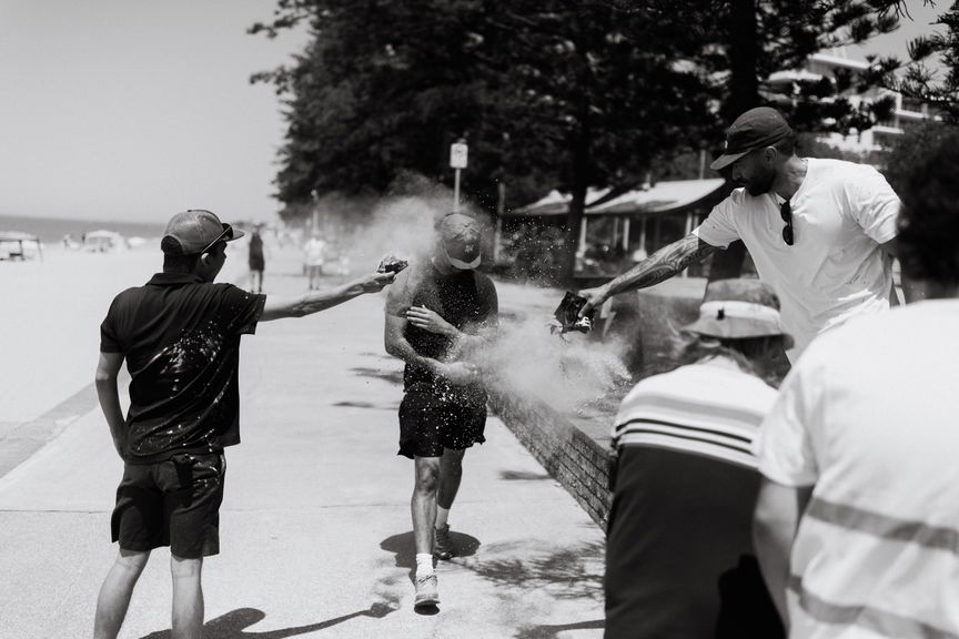 Black and white photo of participants throwing colour powder at a beachside Walk for Awareness event