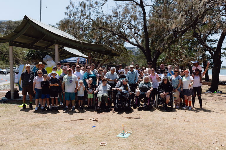 Large group of participants gathered under a marquee at a beachside Walk for Awareness event