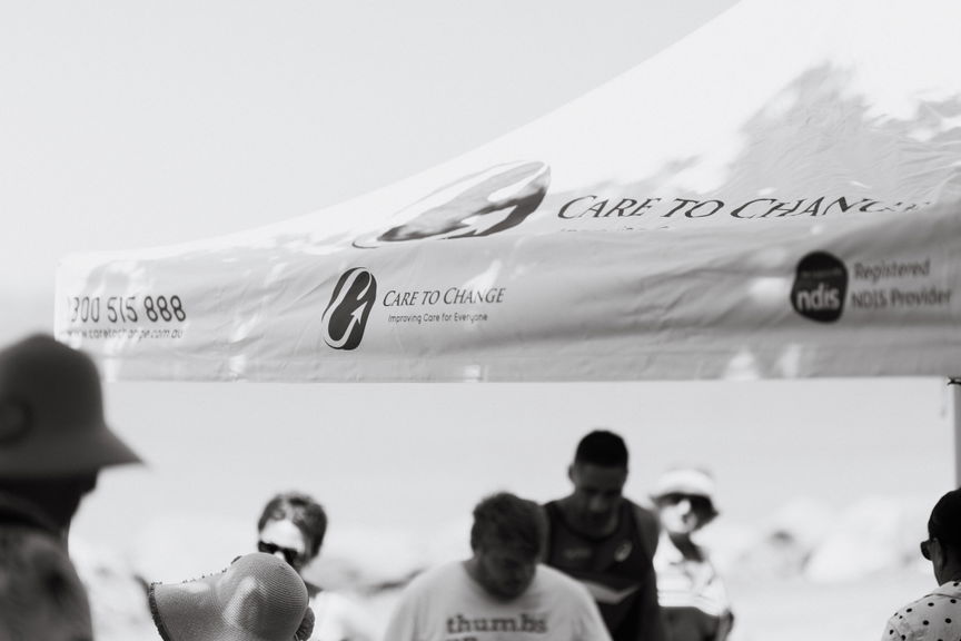Black and white photo of a Care to Change branded marquee at a Walk for Awareness event