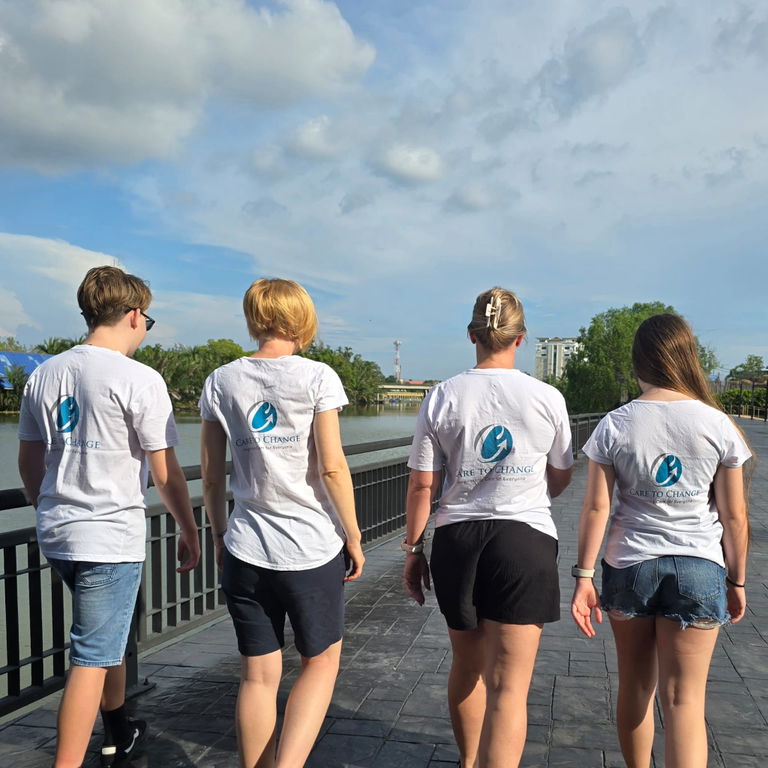Group of participants in matching Care to Change t-shirts walking together along a boardwalk