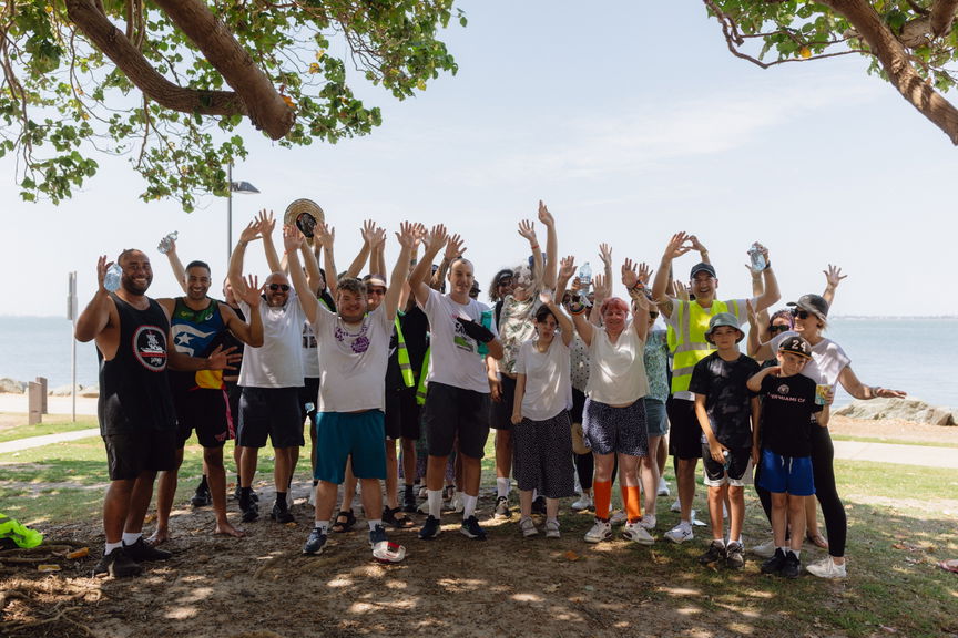Large group of people cheering with their arms raised at an outdoor Care to Change community event