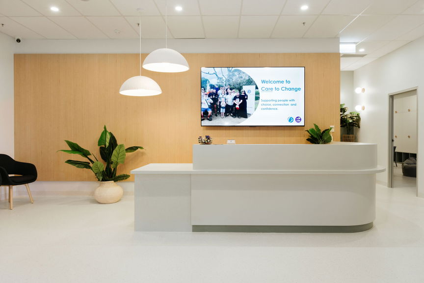 Care to Change Morayfield Hub reception area with a welcome desk and wall-mounted display screen