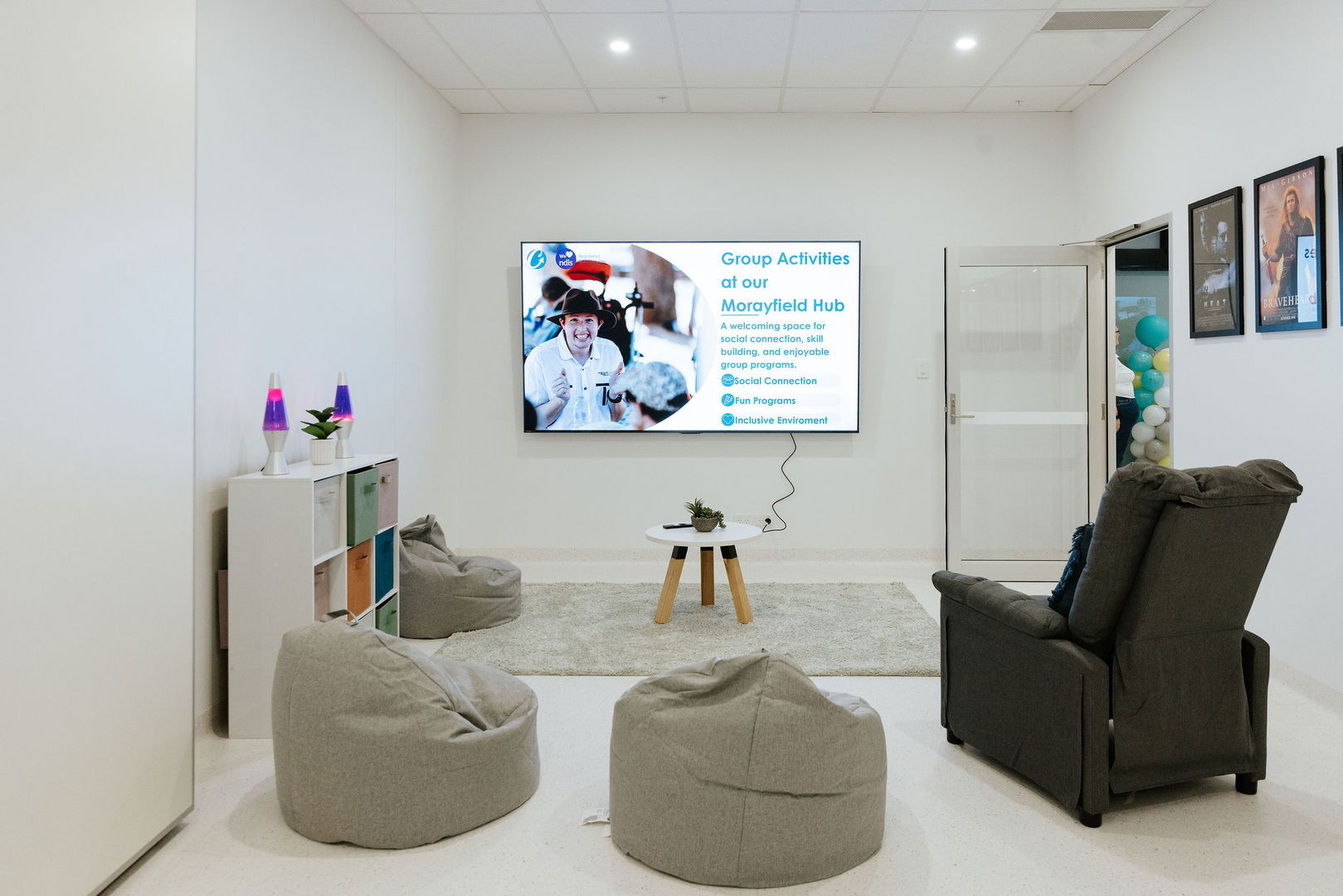 Sensory and gaming lounge with a wall-mounted screen, recliner and bean bags at the Morayfield Hub