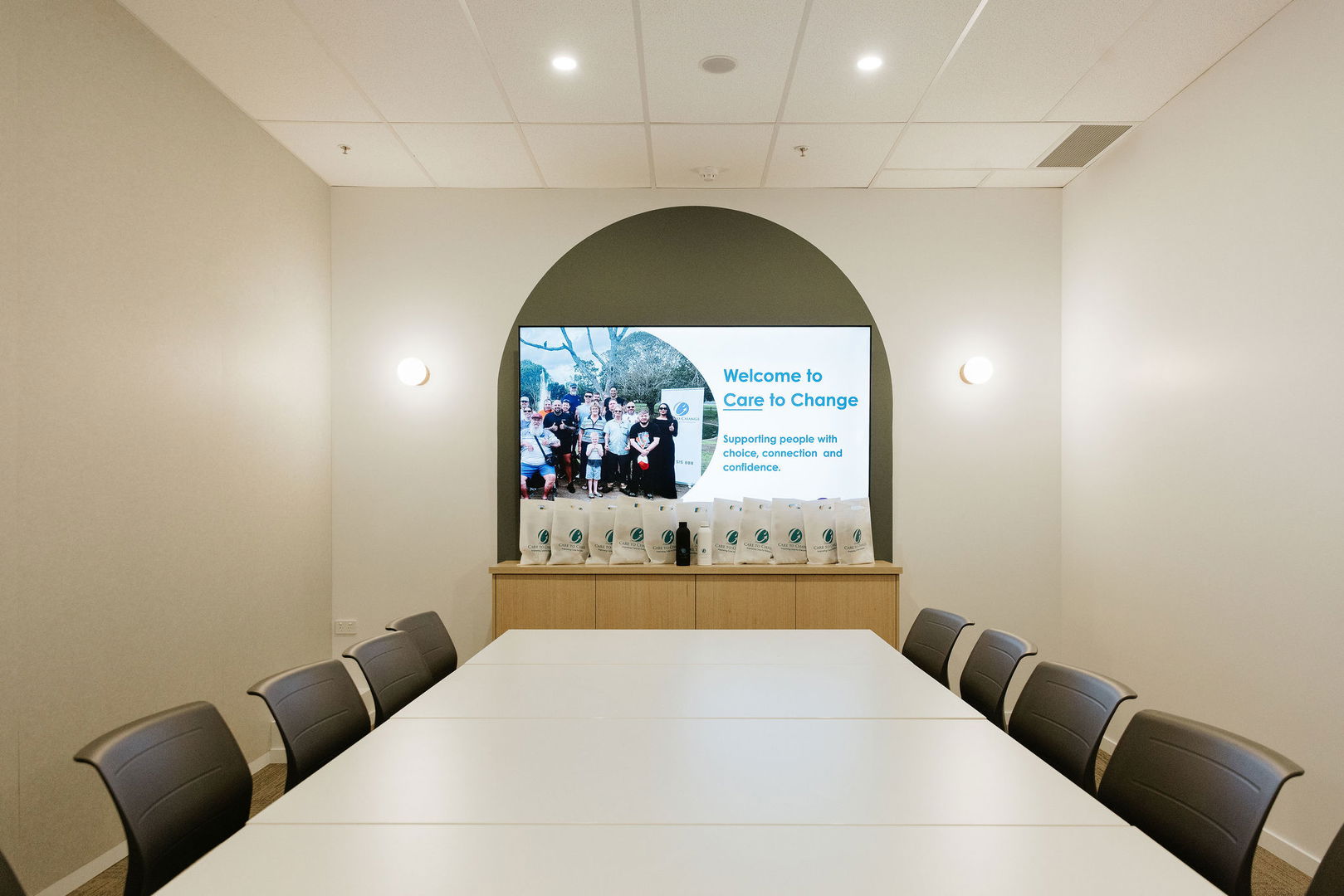 Boardroom with a long meeting table, seating and a wall-mounted presentation screen at the Morayfield Hub