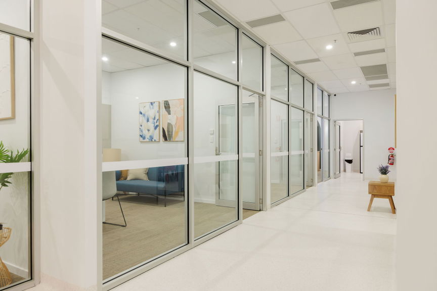 Glass-walled office with a meeting table and seating at the Morayfield Hub