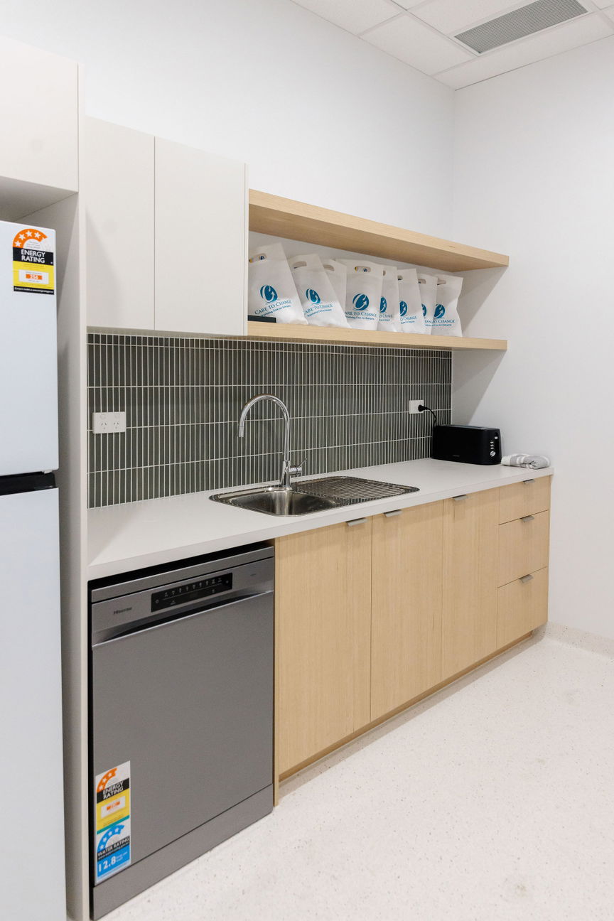 Kitchen with a green tiled splashback, sink and dishwasher at the Morayfield Hub