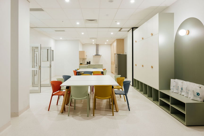 Group activity kitchen and dining area with a long table and colourful chairs at the Morayfield Hub