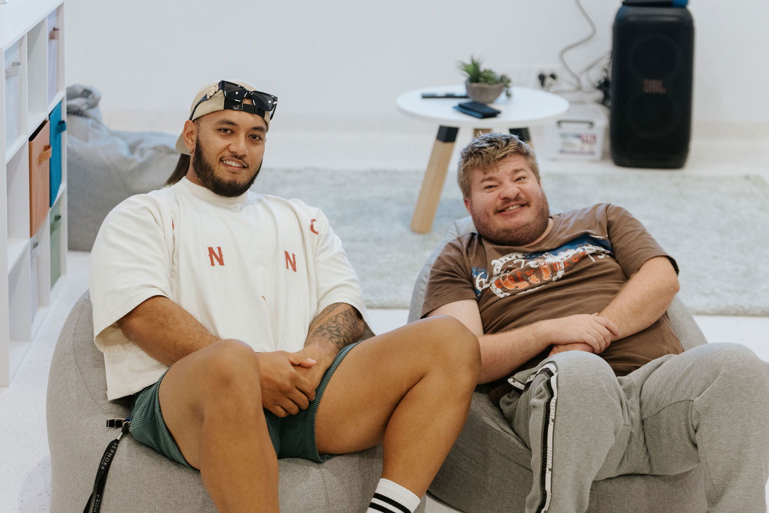 Two men relaxing and smiling on bean bags in the sensory lounge at the Care to Change Morayfield Hub