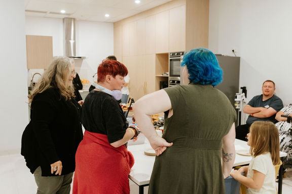 People gathered and chatting around the table in the group activity kitchen at the Care to Change Morayfield Hub