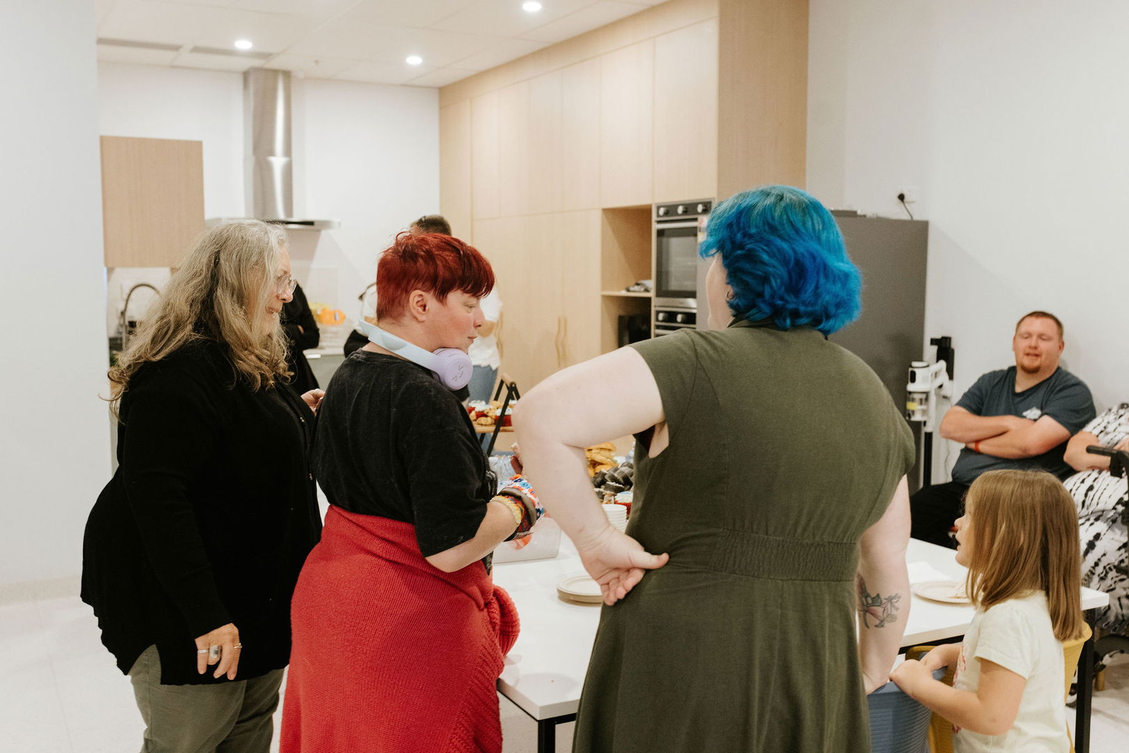 People gathered and chatting around the table in the group activity kitchen at the Care to Change Morayfield Hub
