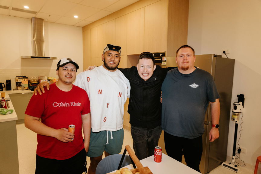 Four men smiling with their arms around each other in the kitchen at the Care to Change Morayfield Hub