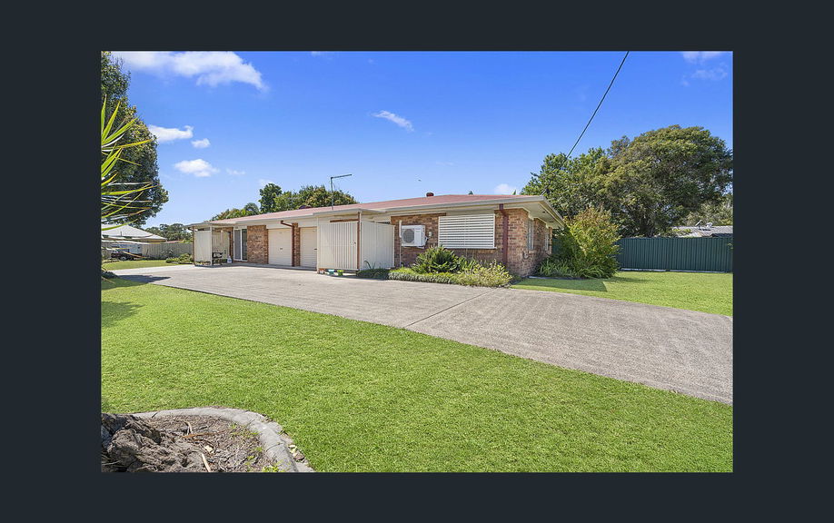 Front of a single-storey brick Care to Change supported home in Caboolture, with a wide concrete driveway and lawn