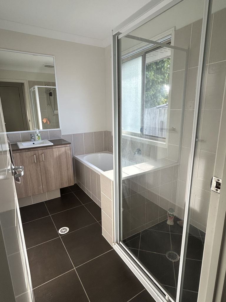 Bathroom with a bath, a separate glass shower and a vanity in the Care to Change supported home in Pimpama