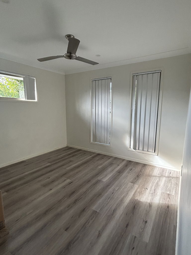 Second vacant bedroom with a ceiling fan and vertical blinds in the Care to Change supported home in Pimpama